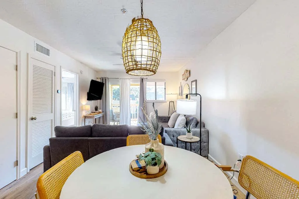 A bright living room with seating around a large white dining table.