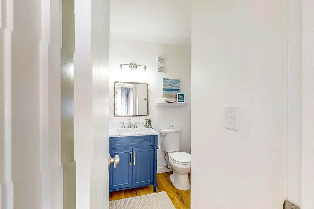 A bathroom with a blue vanity, mirror, and toilet.