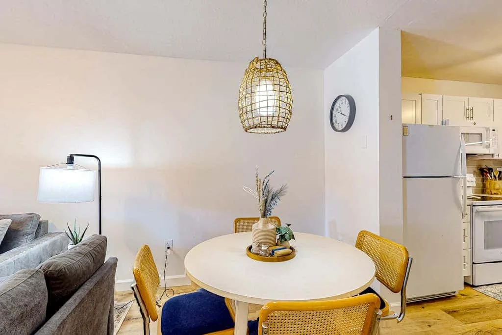 A dining area with a round table beside a living room seating area.