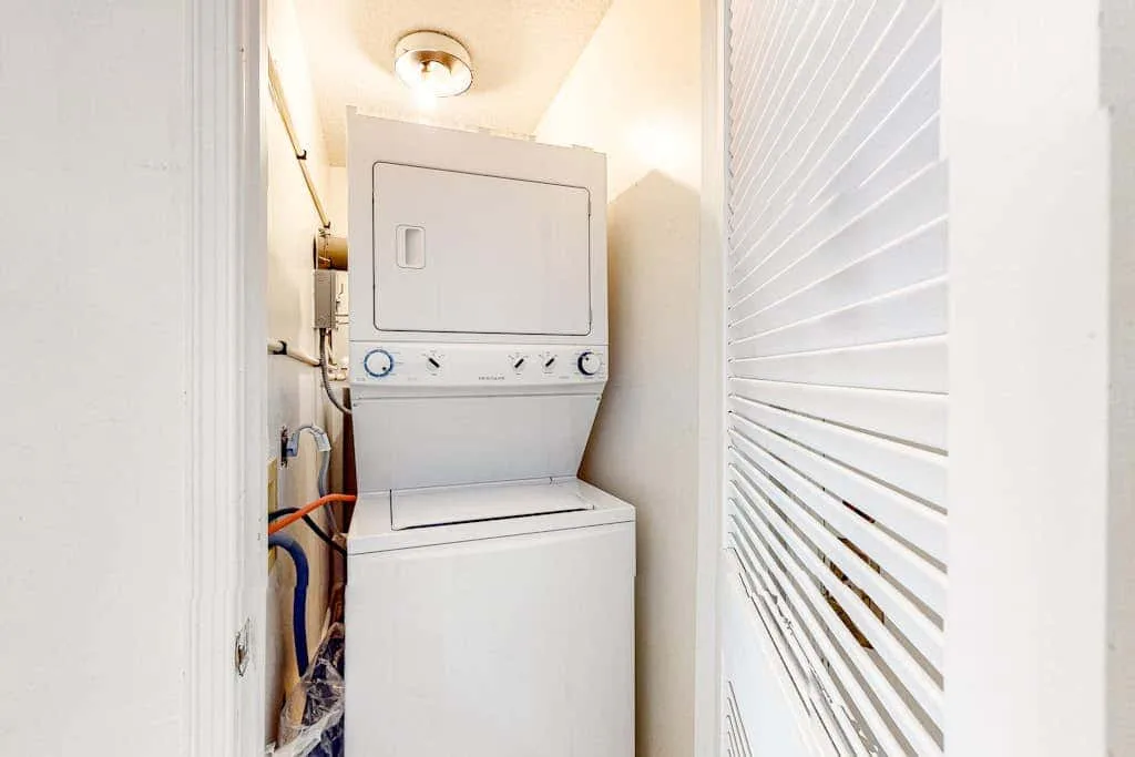 A stacked washer and dryer are installed in a narrow utility closet.