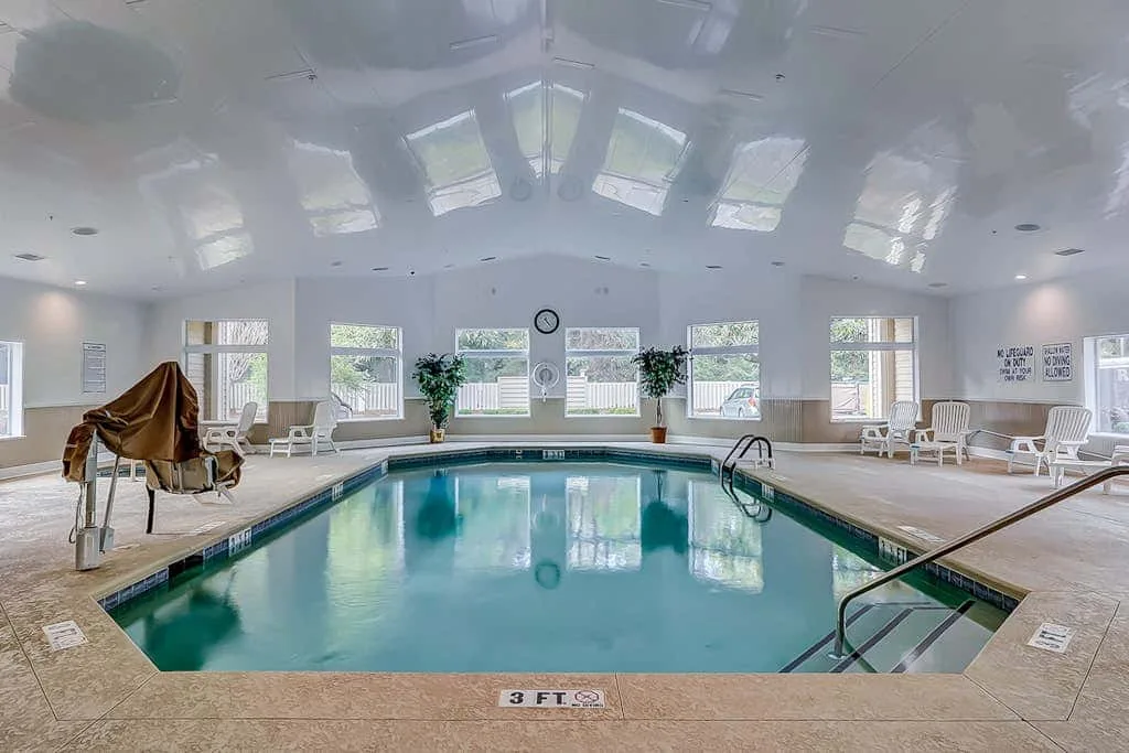 An indoor swimming pool sits beneath a bright ceiling with skylights.