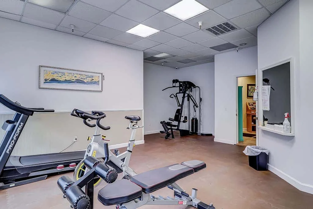 A small gym with exercise equipment and a framed picture on the wall.
