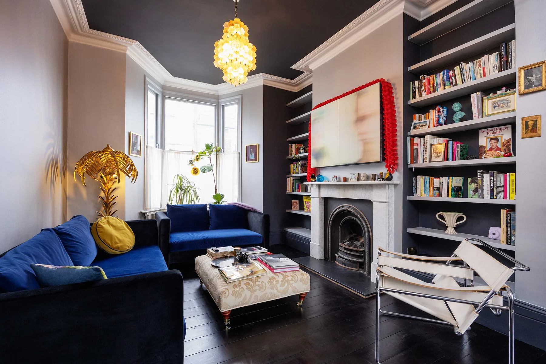 Una sala de estar con asientos azules, una chimenea y estanterías.