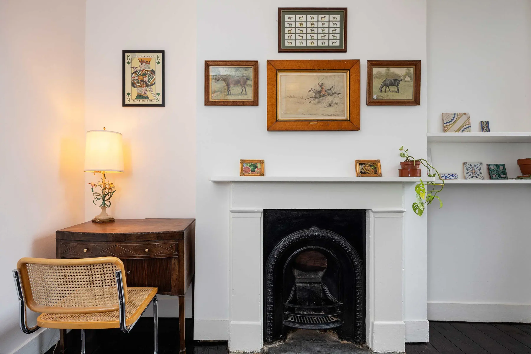 Una sala de estar con chimenea, cuadros enmarcados y una lámpara de mesa.