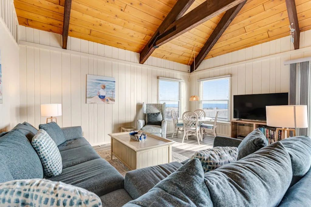 A bright living room with seating, a coffee table, and large windows.