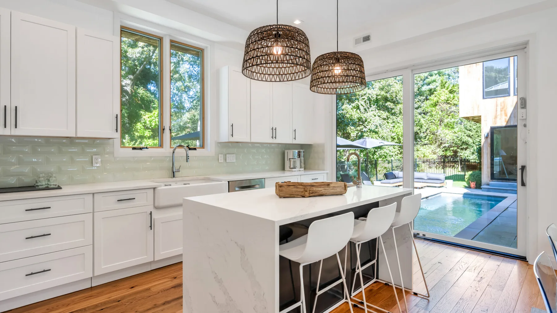 A bright kitchen with a central island and large windows overlooking a pool.