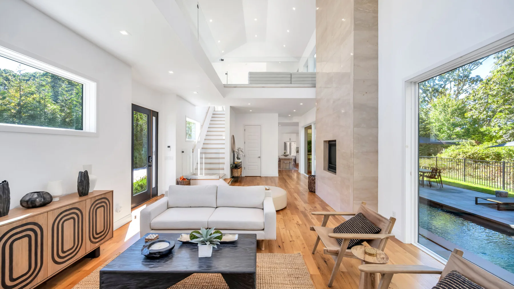 A bright living room opens onto a patio with a pool and greenery.