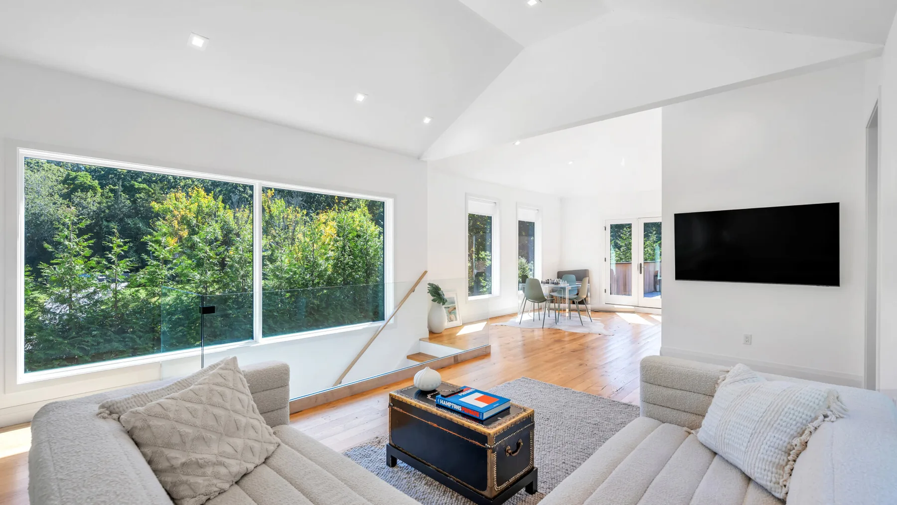 A bright living room with large windows, seating, and a coffee table.