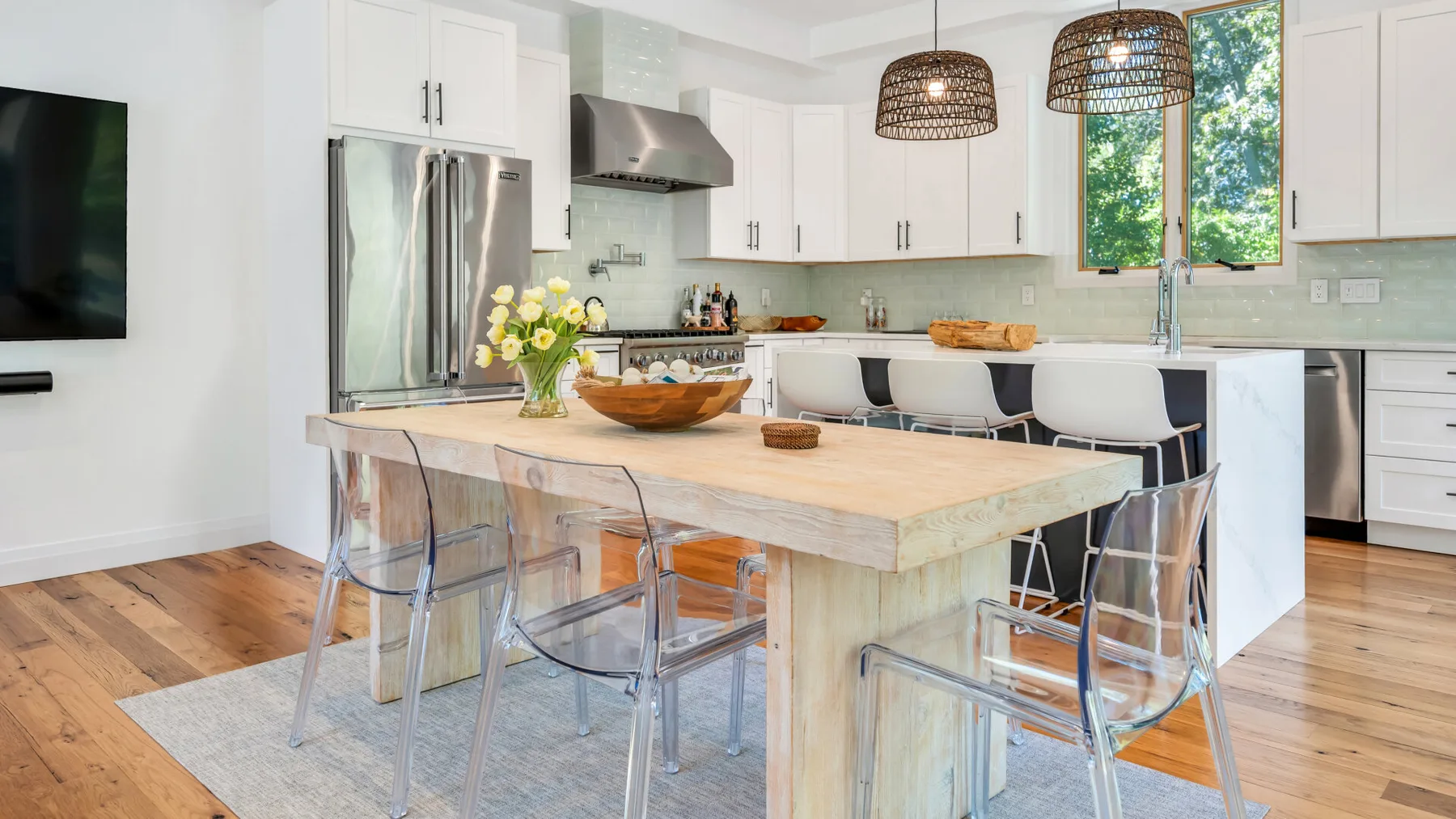 A bright kitchen with a large island, white cabinetry, and dining seating.