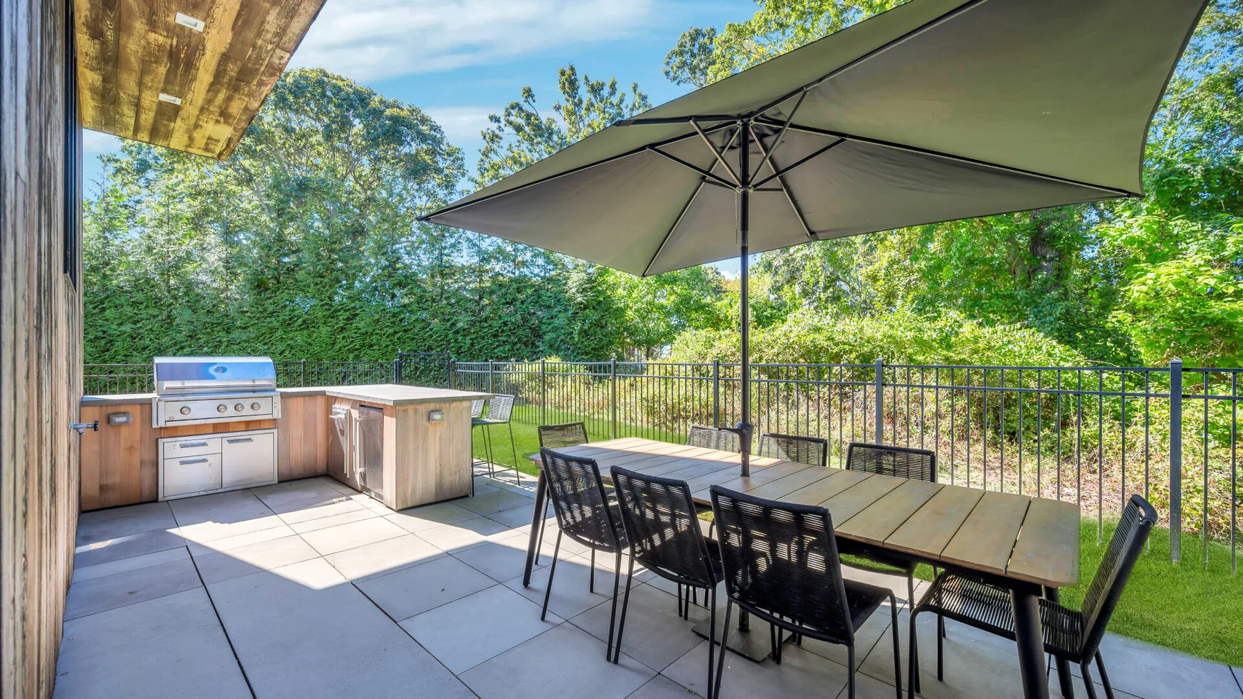 An outdoor dining area with a table, chairs, and a large umbrella.