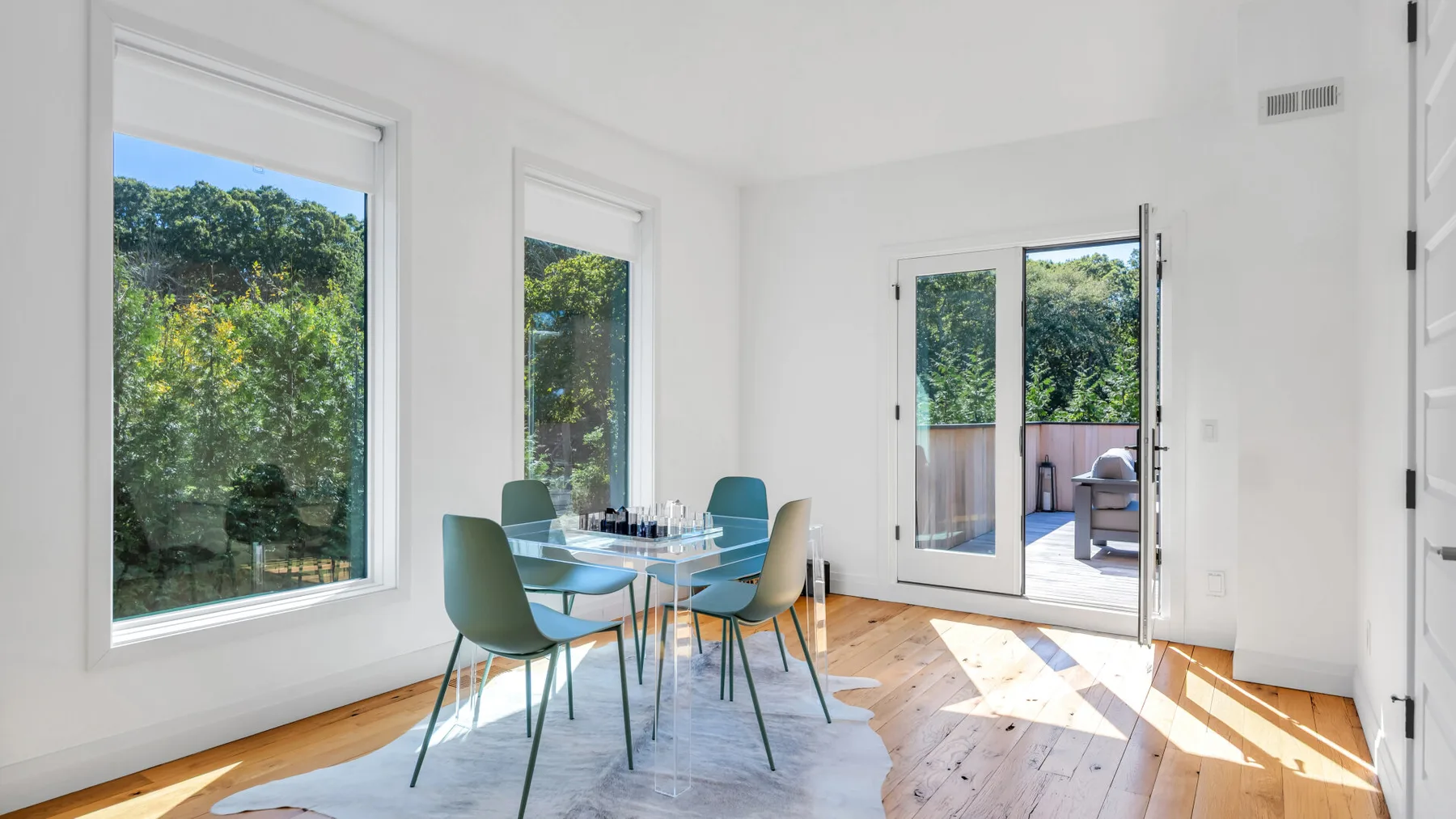 A bright dining area with a table, seating, large windows, and an open door to a patio.