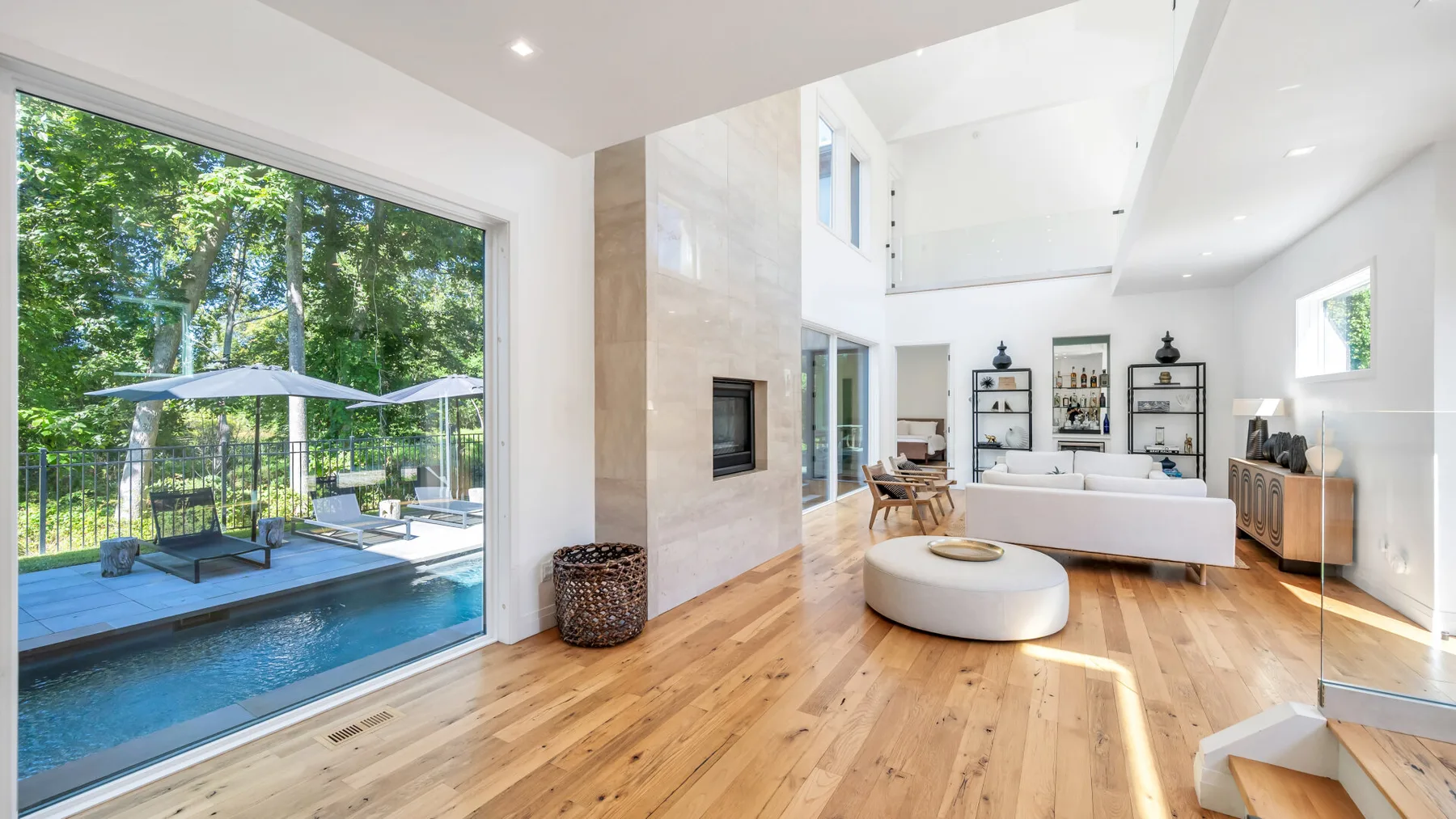 A bright living room opens onto a patio and swimming pool through large windows.