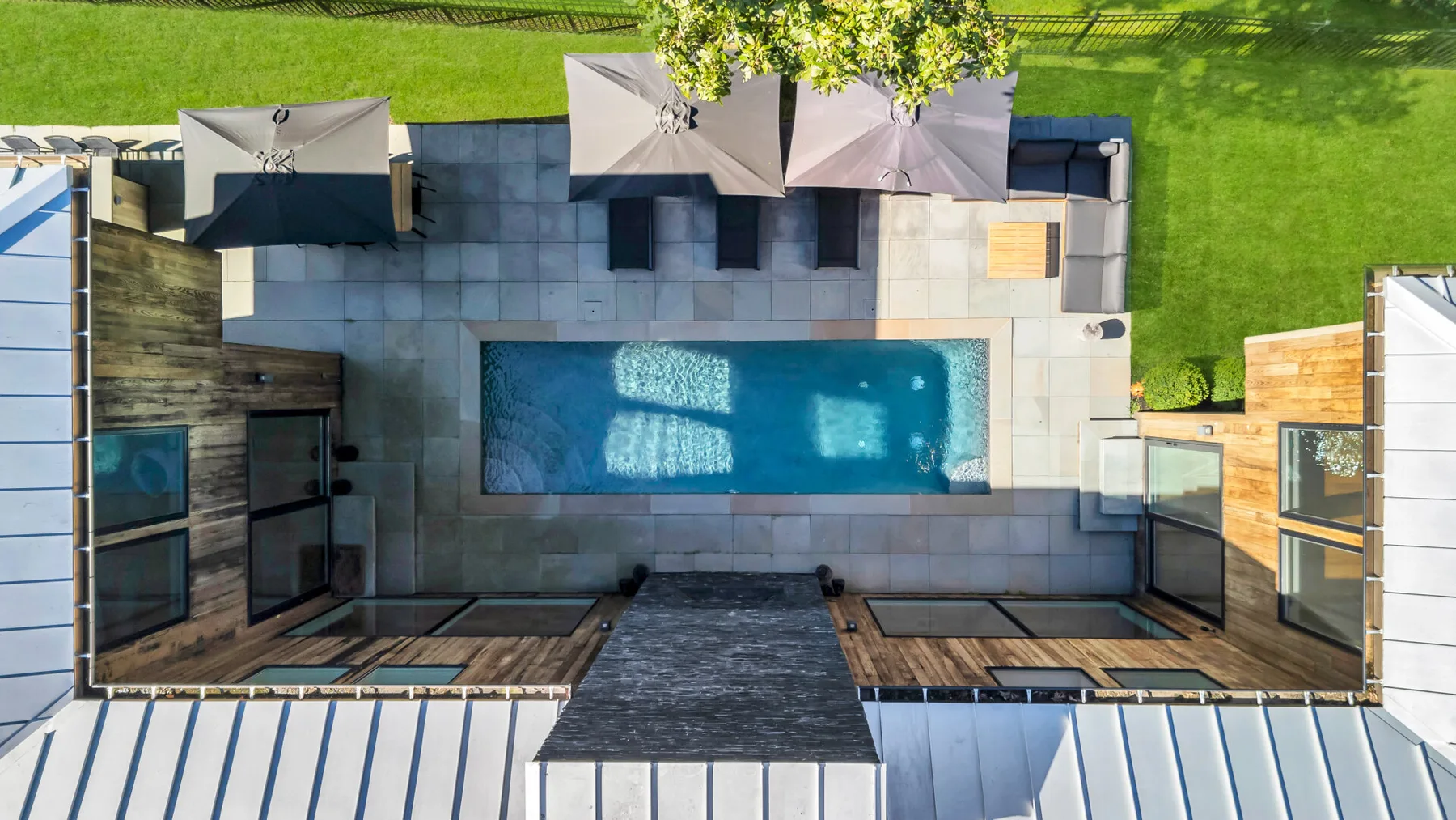 An overhead view of a swimming pool surrounded by paved patio and outdoor seating.