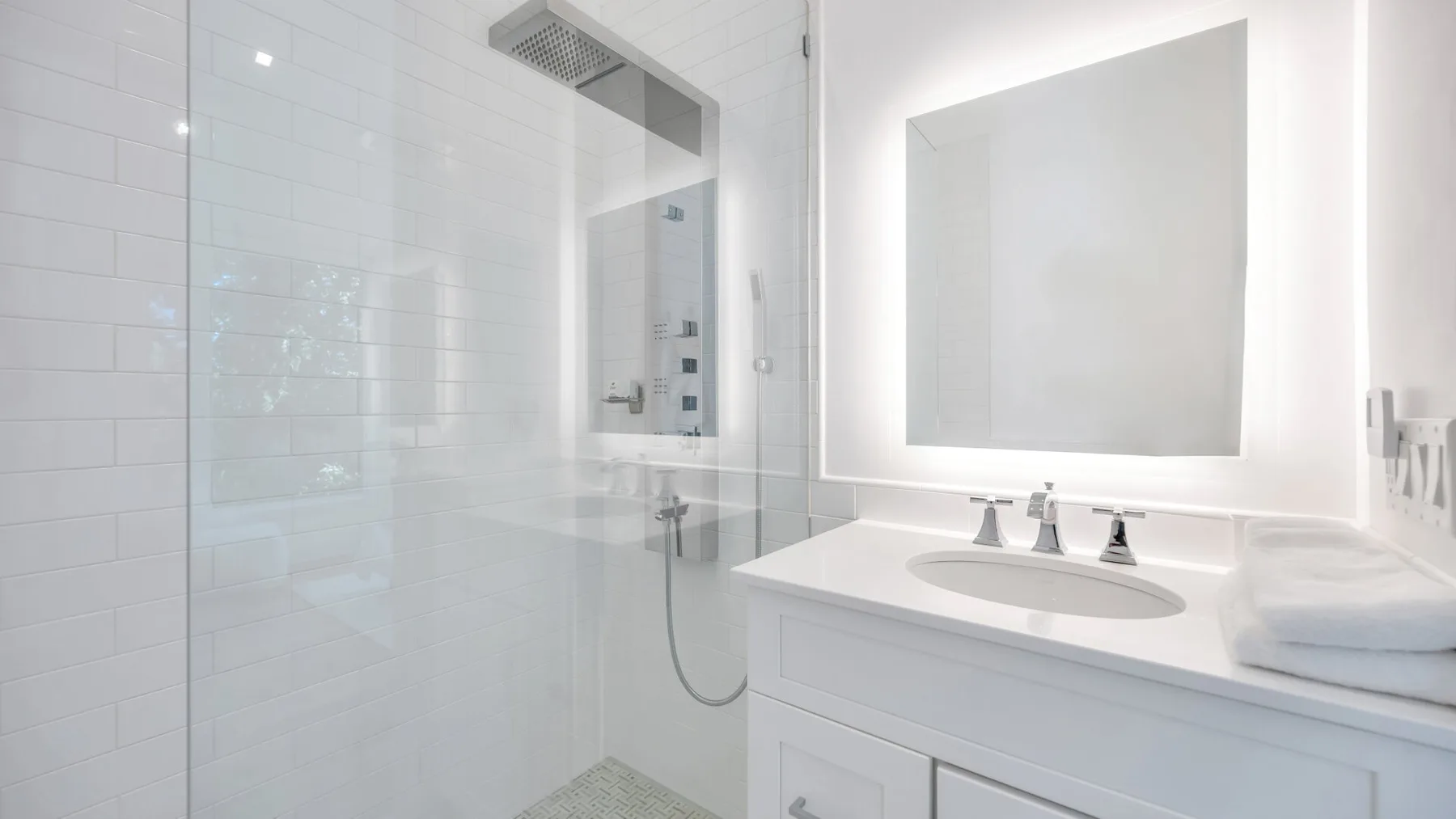 A bright white bathroom with a glass shower and a sink vanity.