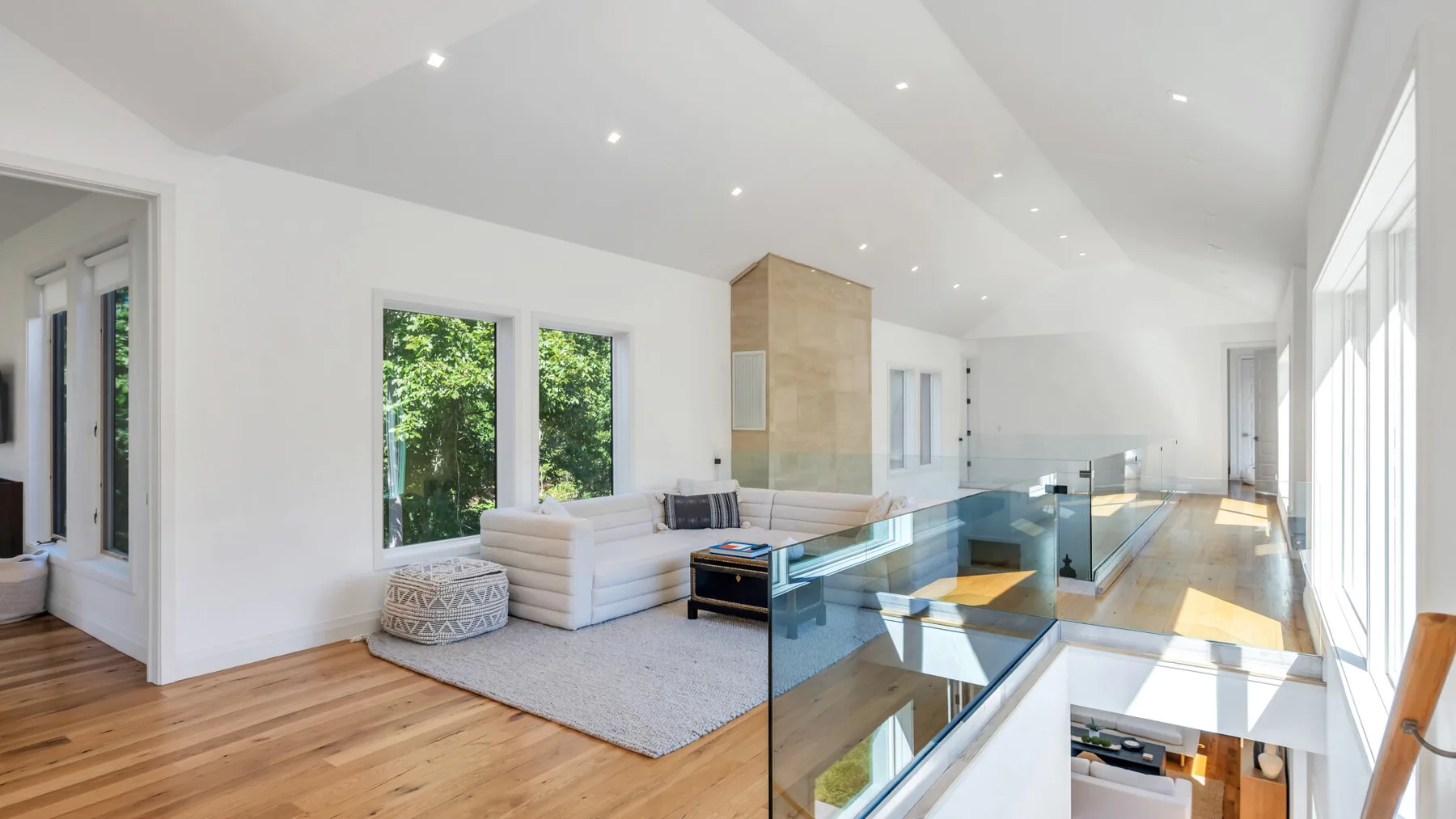 A bright living area with seating beside a glass-railed staircase.
