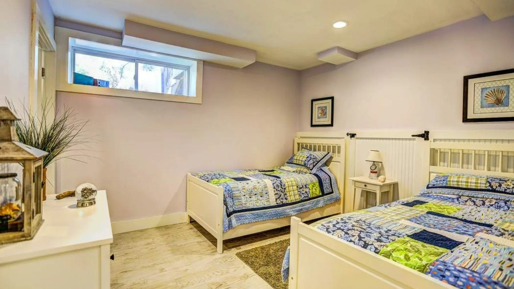 A bedroom with two single beds, patterned bedding, and a small bedside table.