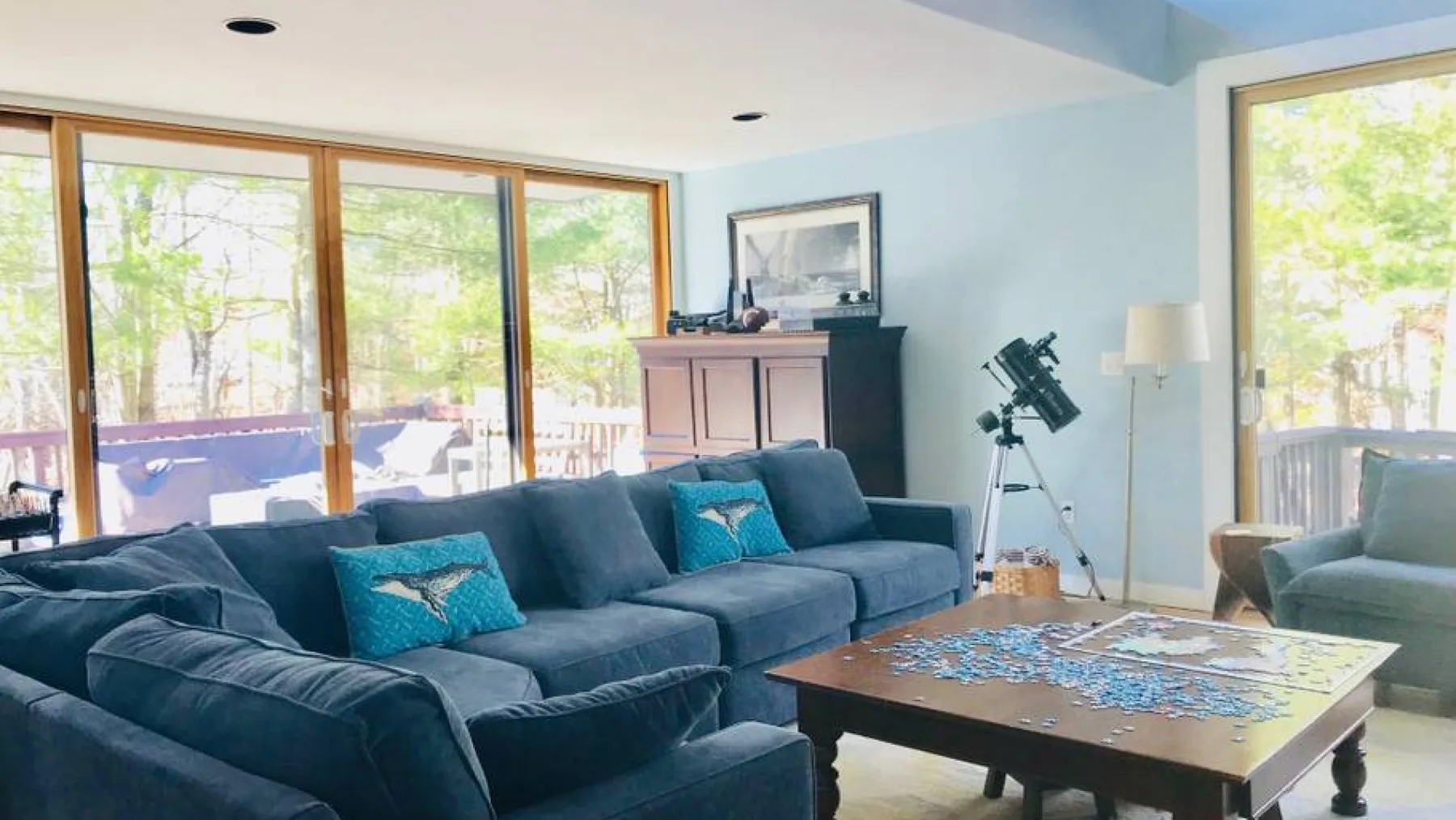 A bright living room with seating, a coffee table, and large windows.