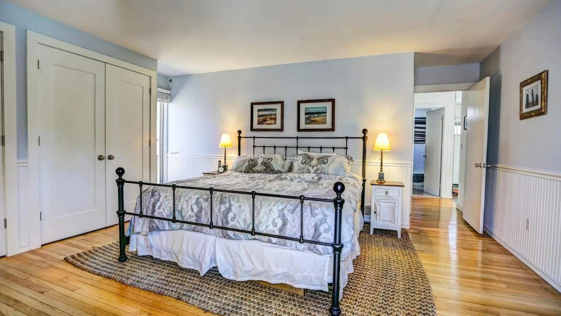A bedroom with a metal-framed bed, bedside tables, and hardwood flooring.
