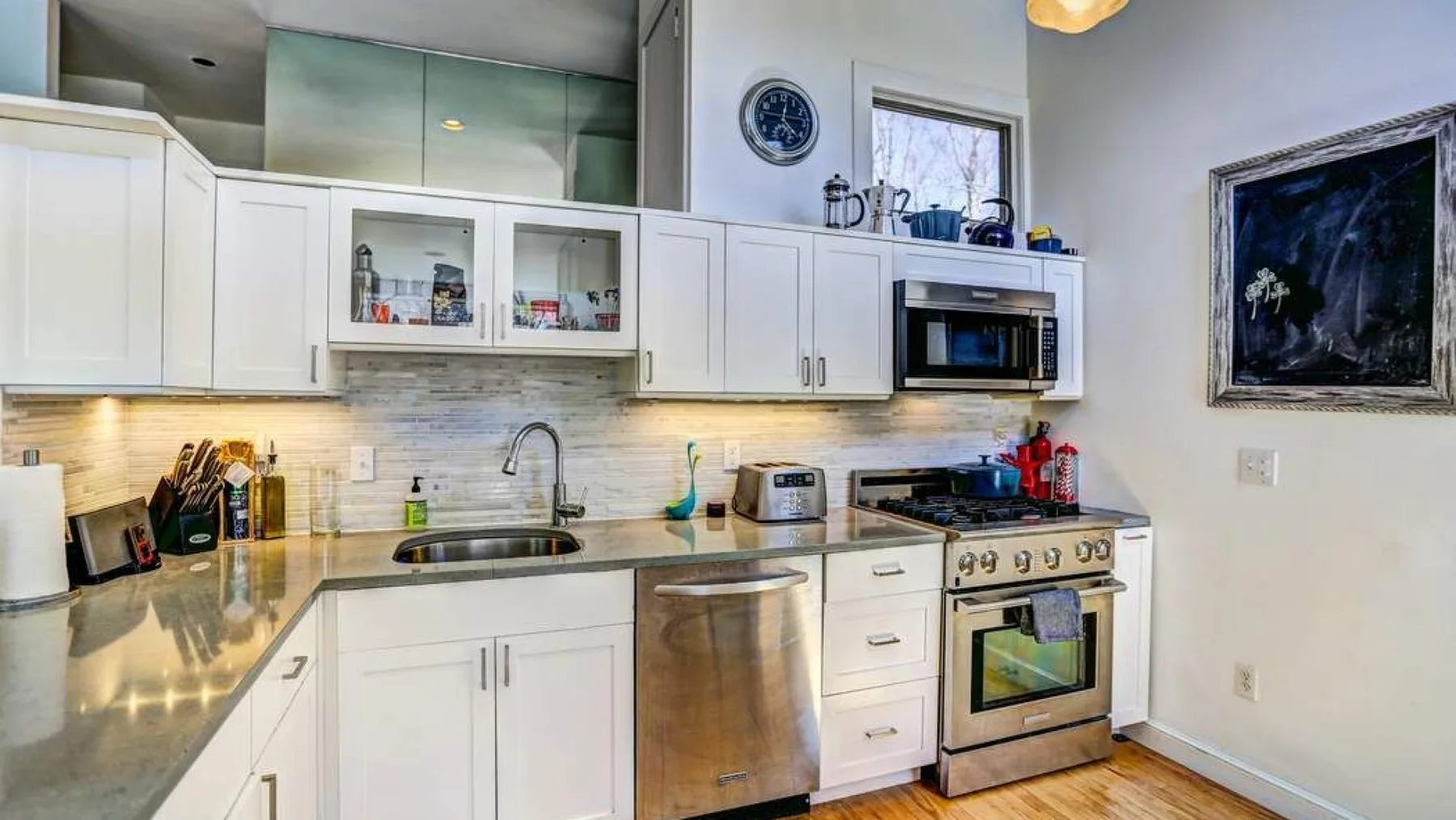 A bright kitchen with white cabinets, a countertop, and stainless steel appliances.