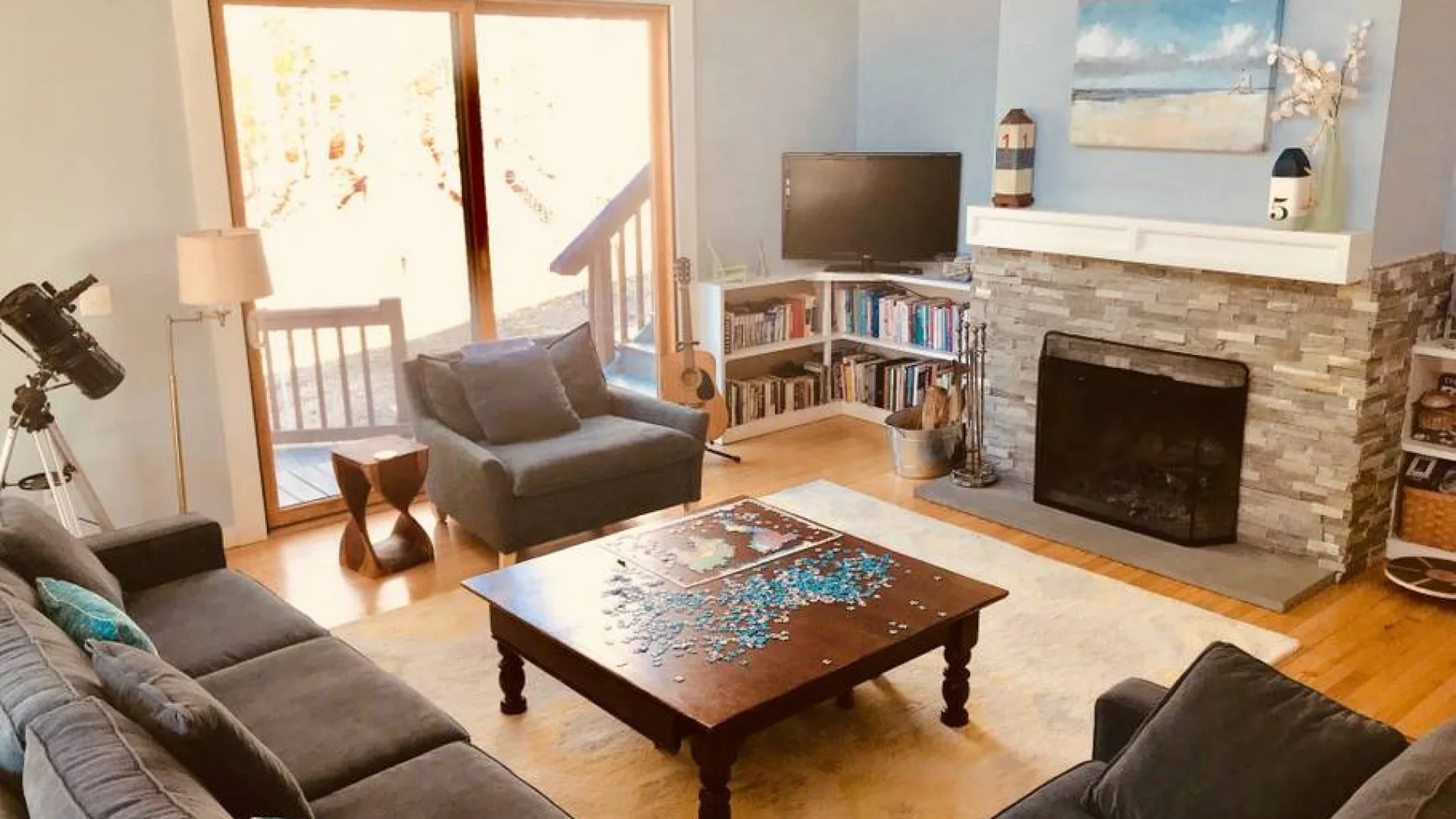 A living room with seating, a coffee table, and a stone fireplace.