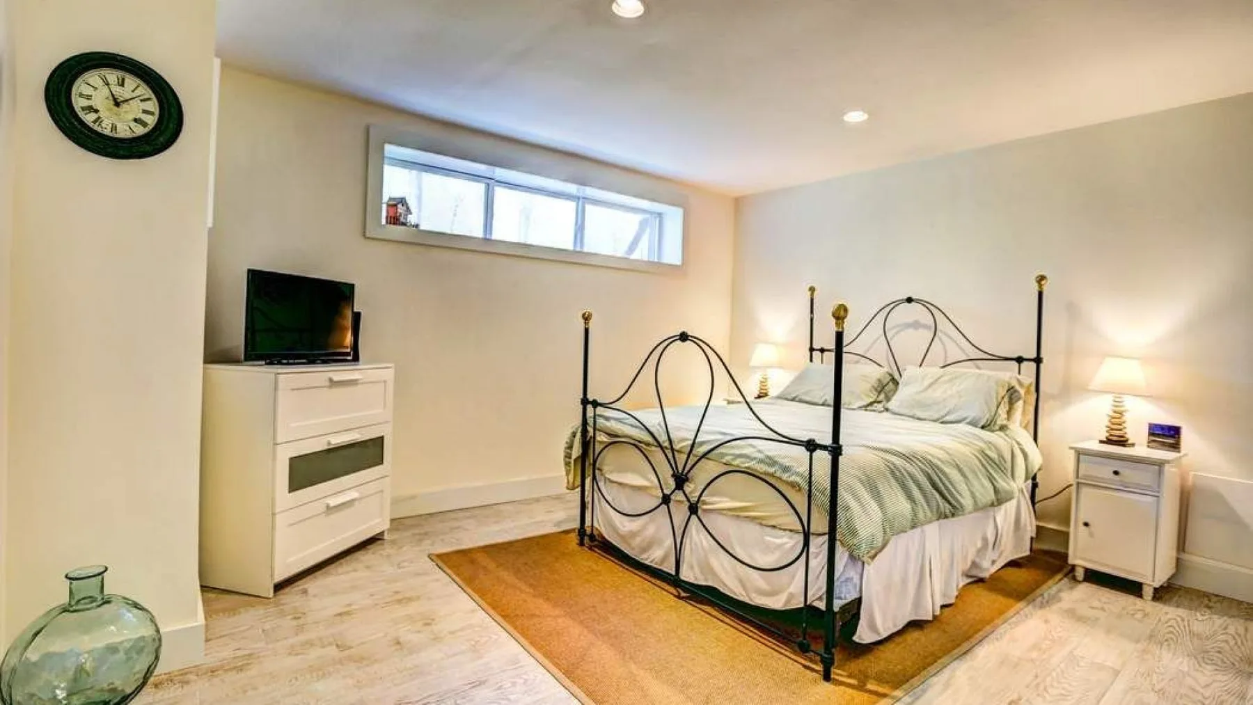A bedroom with a metal bed, bedside table, and television.
