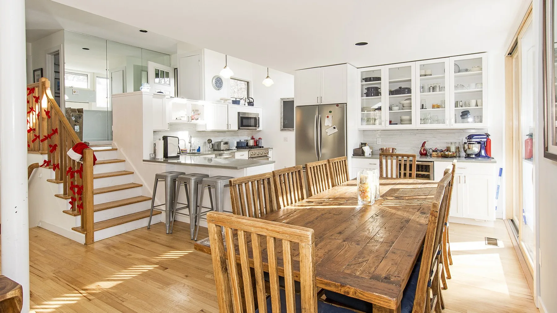 A bright open-plan kitchen and dining area with a long wooden table.