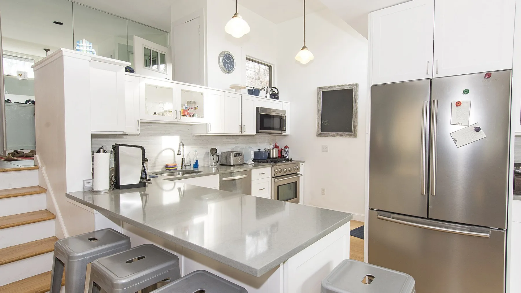 A bright kitchen with a large island, white cabinetry, and stainless steel appliances.