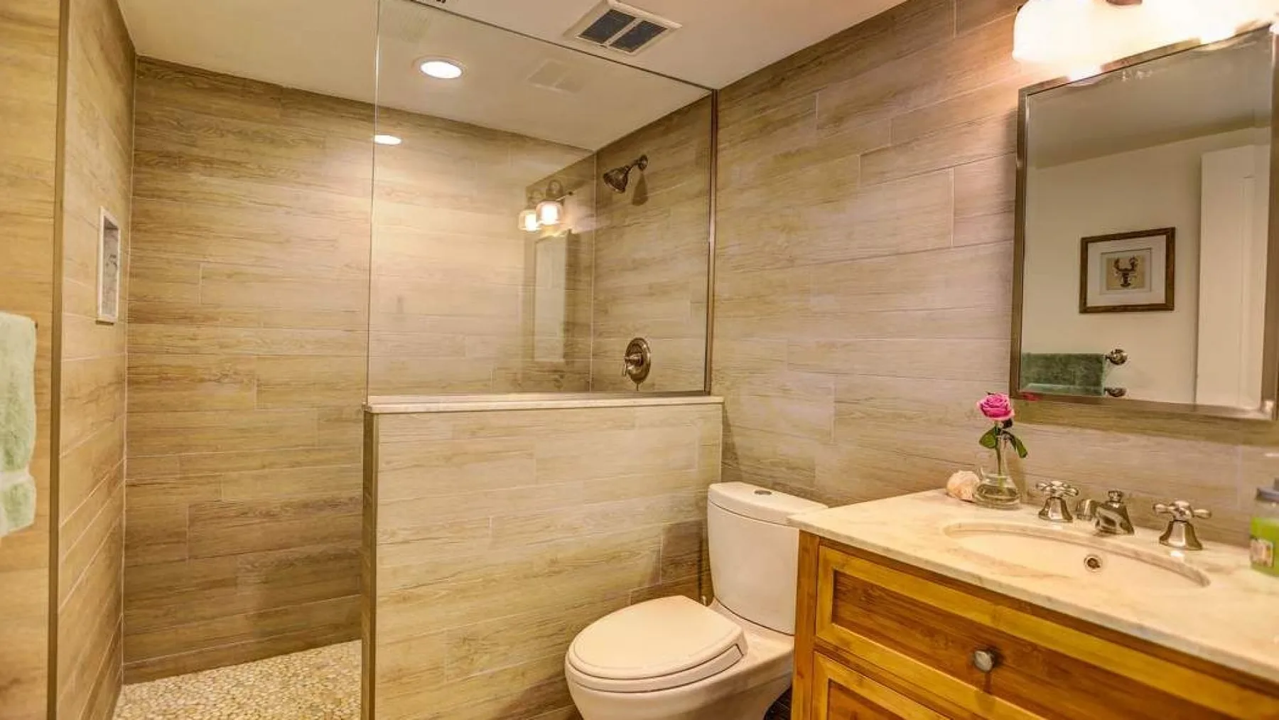 A beige-tiled bathroom with a shower area and a sink vanity.