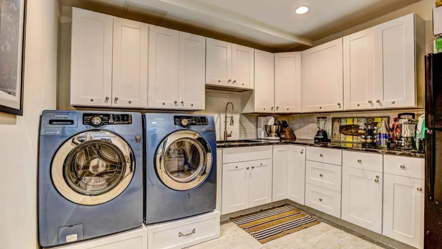 A laundry room with front-loading machines and white cabinets.