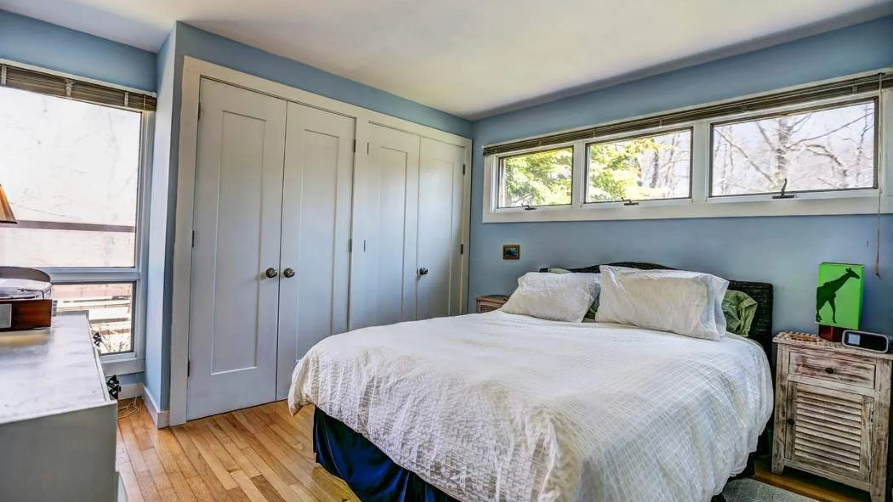 A bedroom with a bed, built-in closets, and windows along the walls.