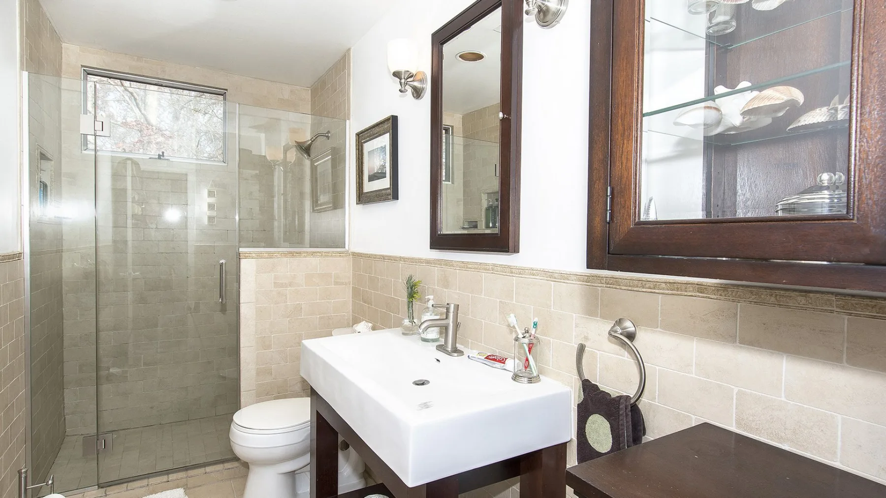 A bathroom with a glass shower, toilet, and sink.