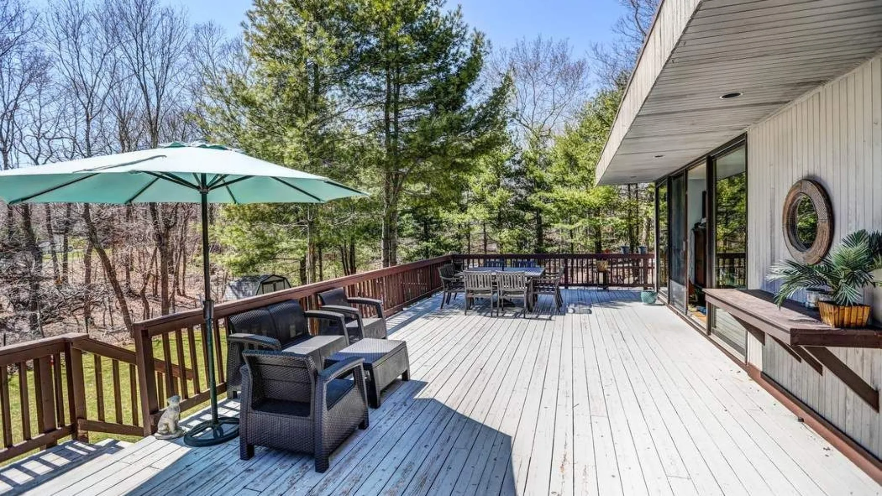A spacious outdoor deck has seating, a table, and a green umbrella.