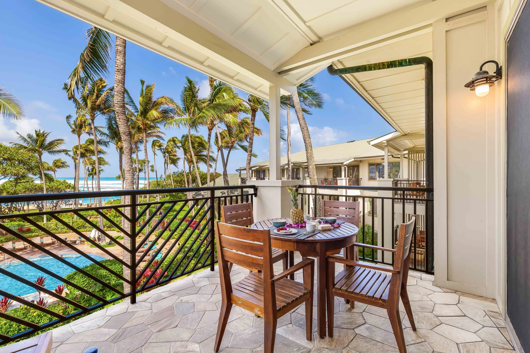 Una zona de comedor exterior cubierta da a palmeras y una piscina.
