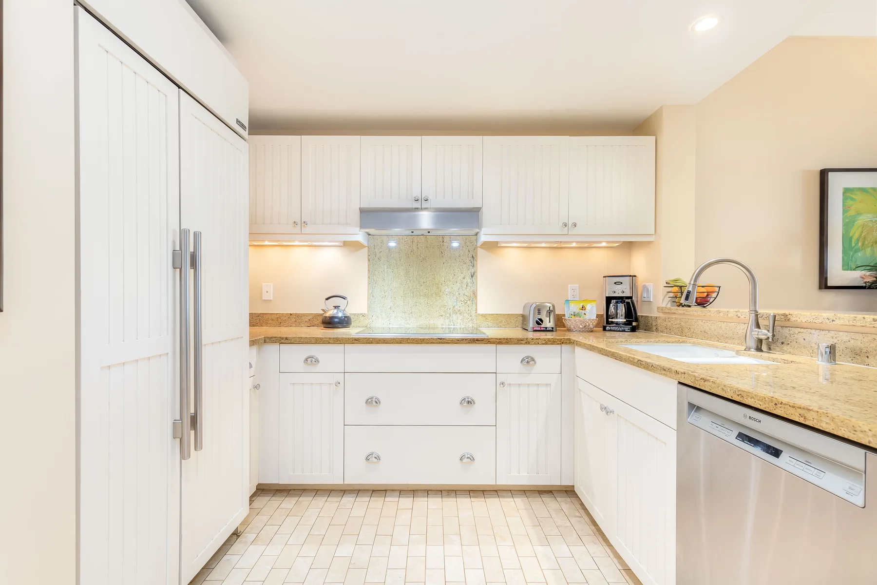 Una cocina luminosa con gabinetes blancos, encimera y fregadero.