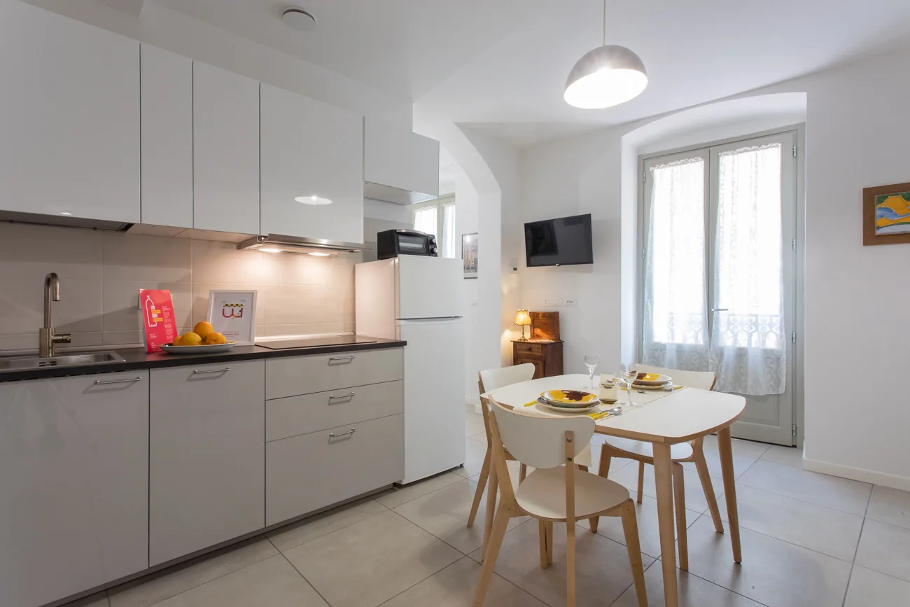 Cocina y comedor luminosos con una mesa junto a ventanas altas.