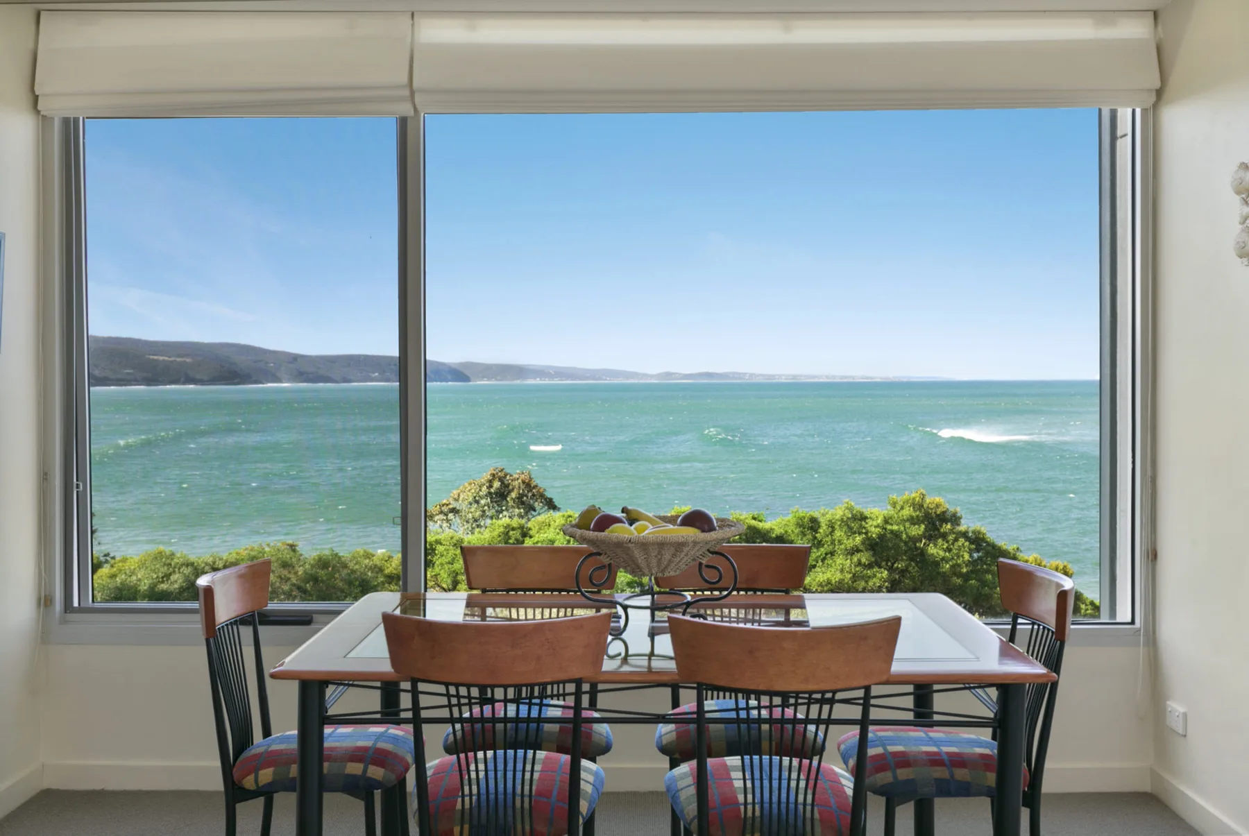 Un comedor con mesa y sillas da a una gran ventana con vistas al mar.