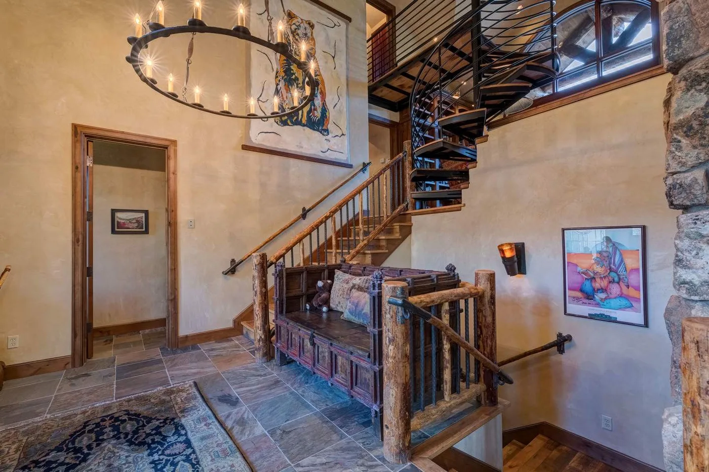 A stone-floored interior features a wooden staircase and an upper-level railing.