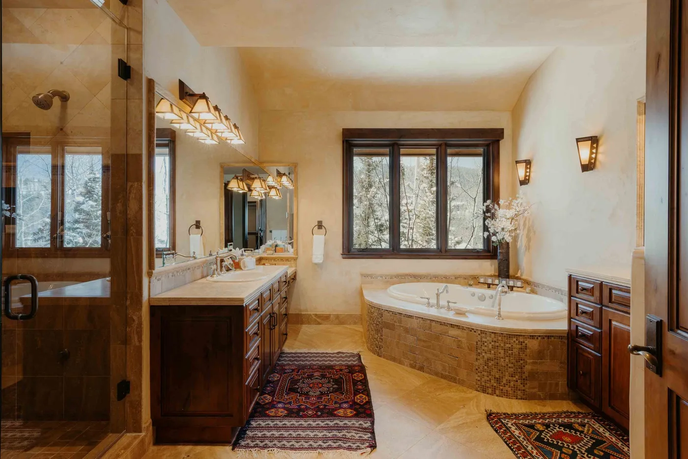 A spacious bathroom with a bathtub, vanity, and window overlooking trees.