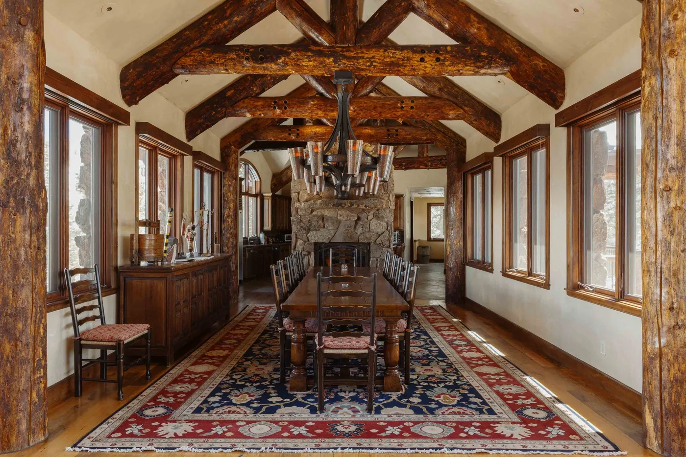 A dining room with a long table beneath exposed wooden beams.