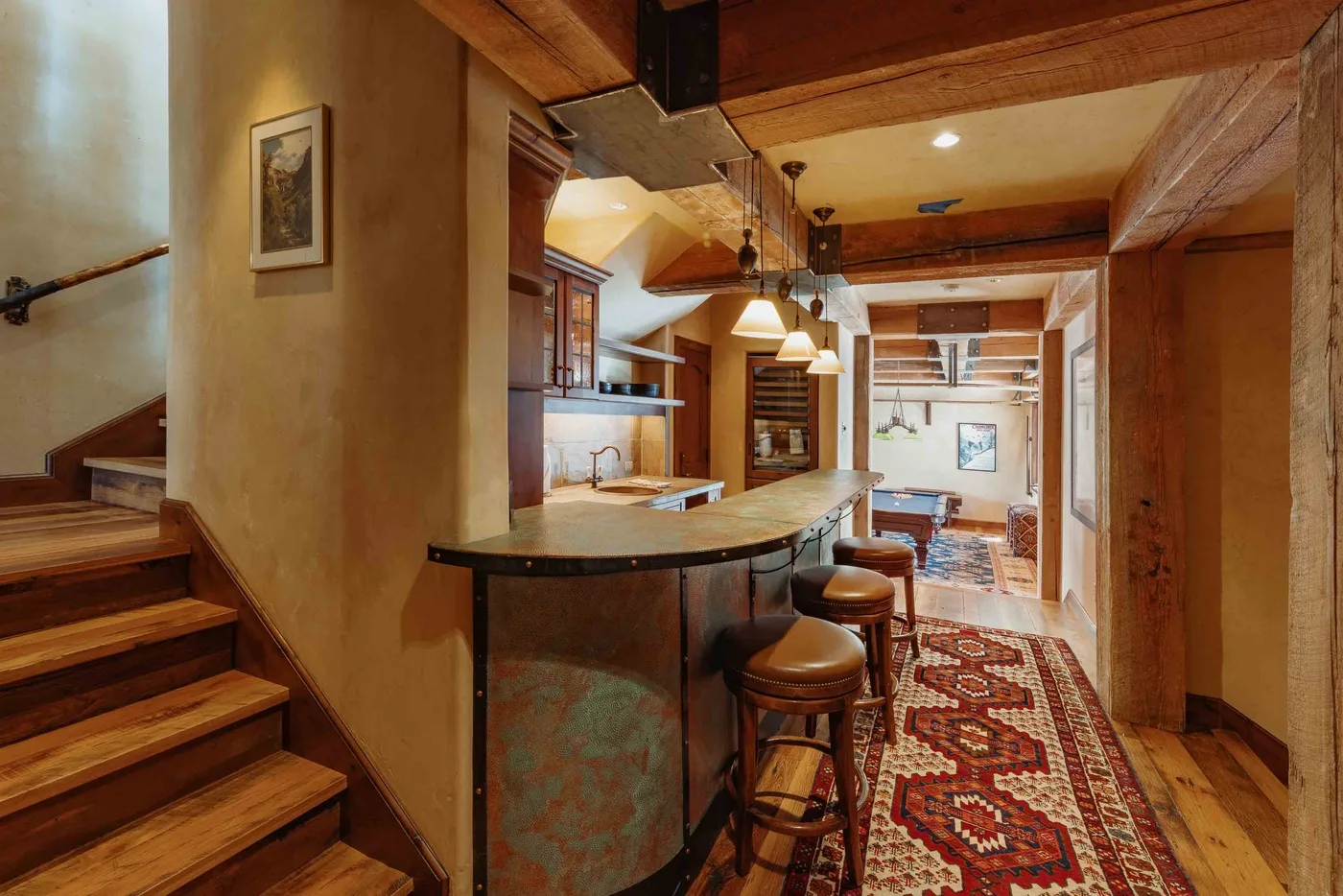 A wood-paneled room with a curved counter, stools, and a patterned rug.