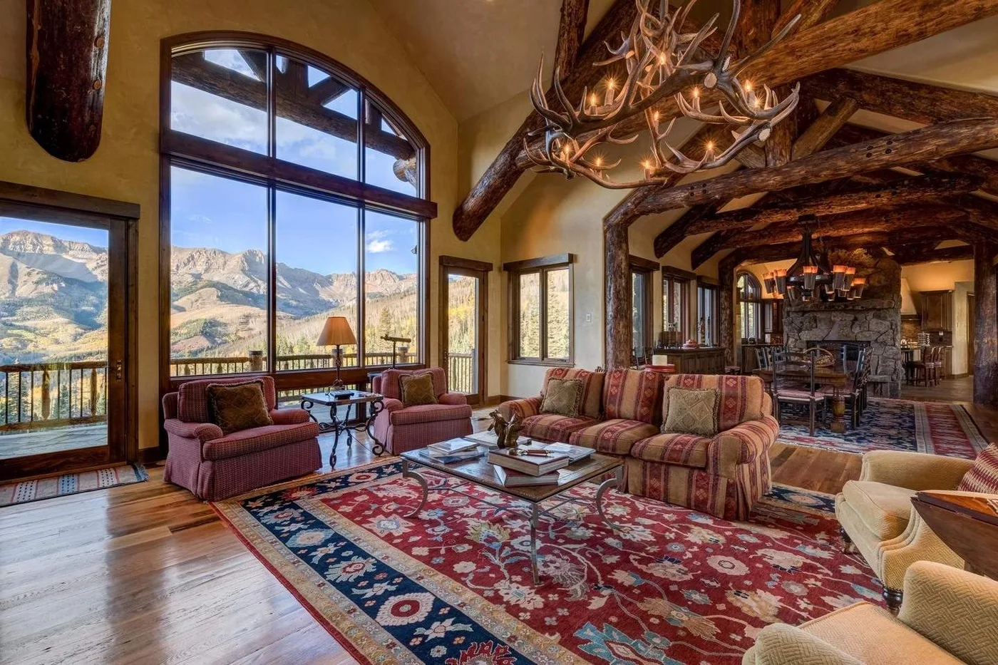 A spacious living room with seating, a patterned rug, and mountain views through large windows.