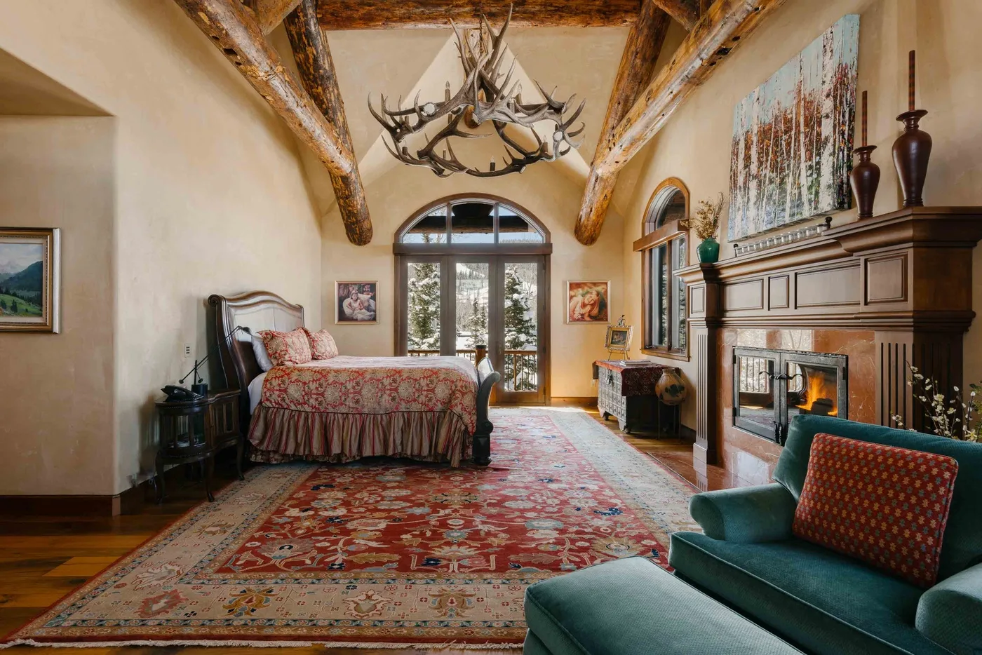 A bedroom with a bed, a fireplace, and a large patterned rug.