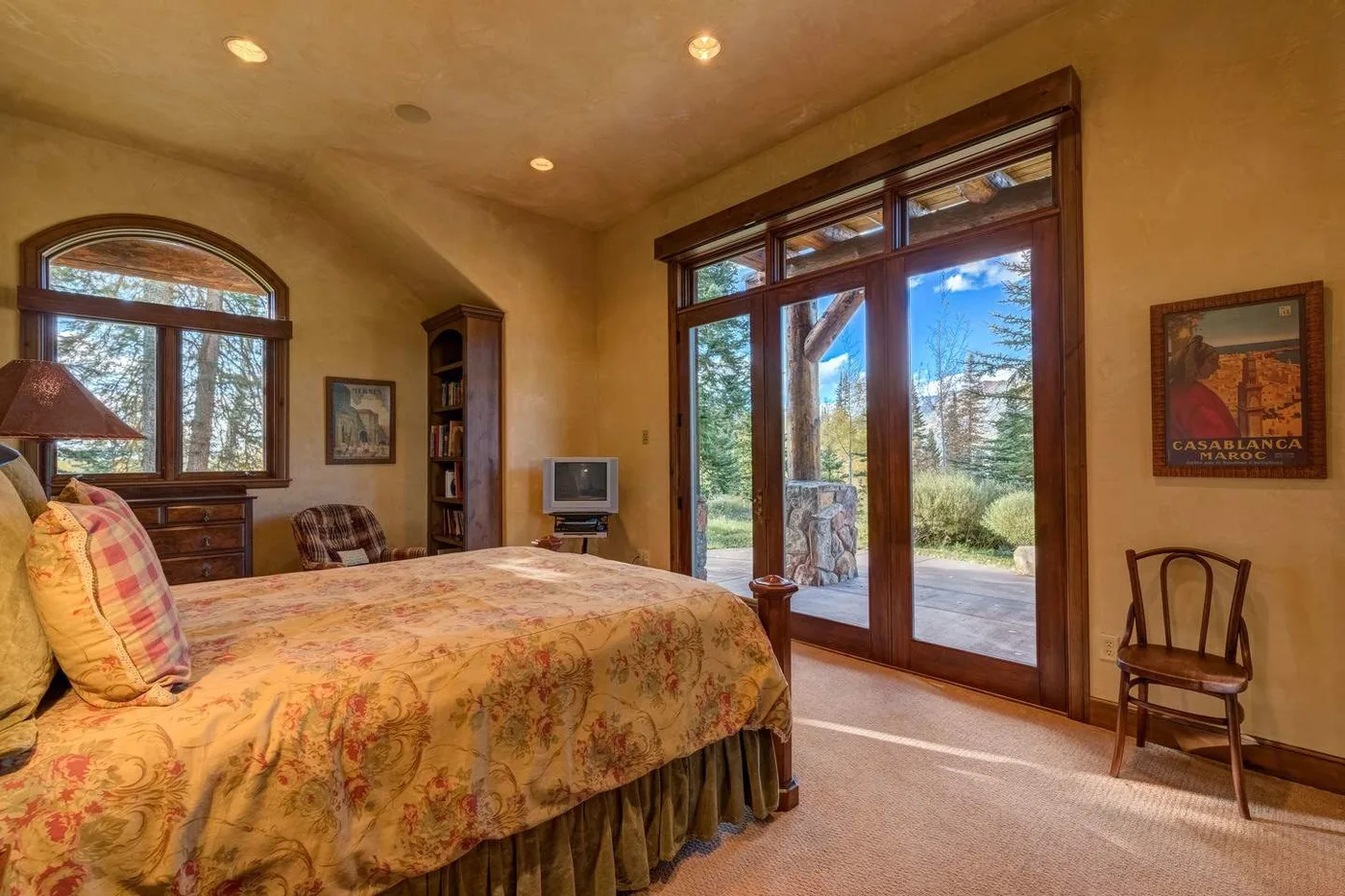 A bedroom with a large bed beside glass doors opening onto a patio.