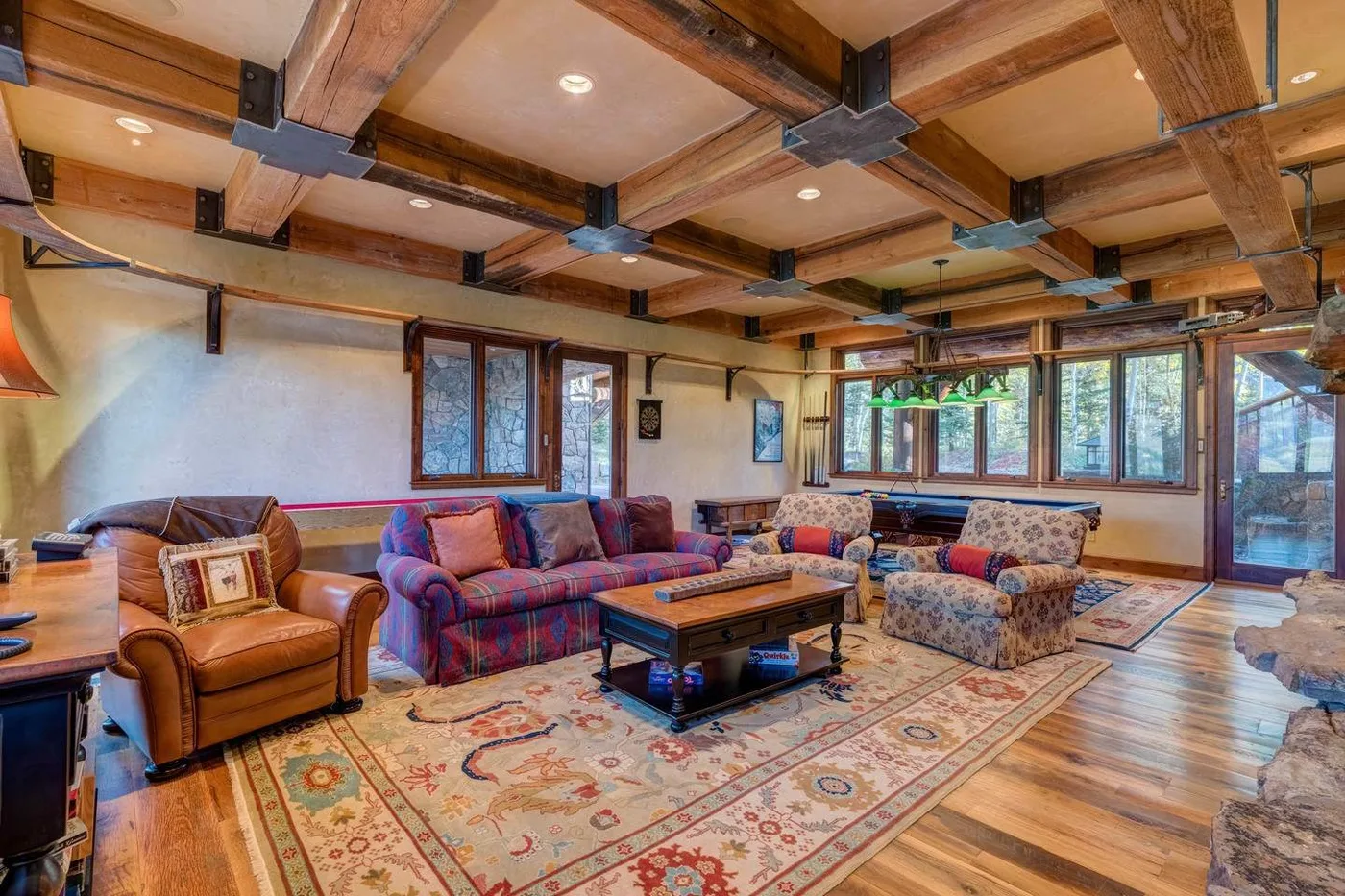A spacious living room with seating, a wooden coffee table, and large windows.