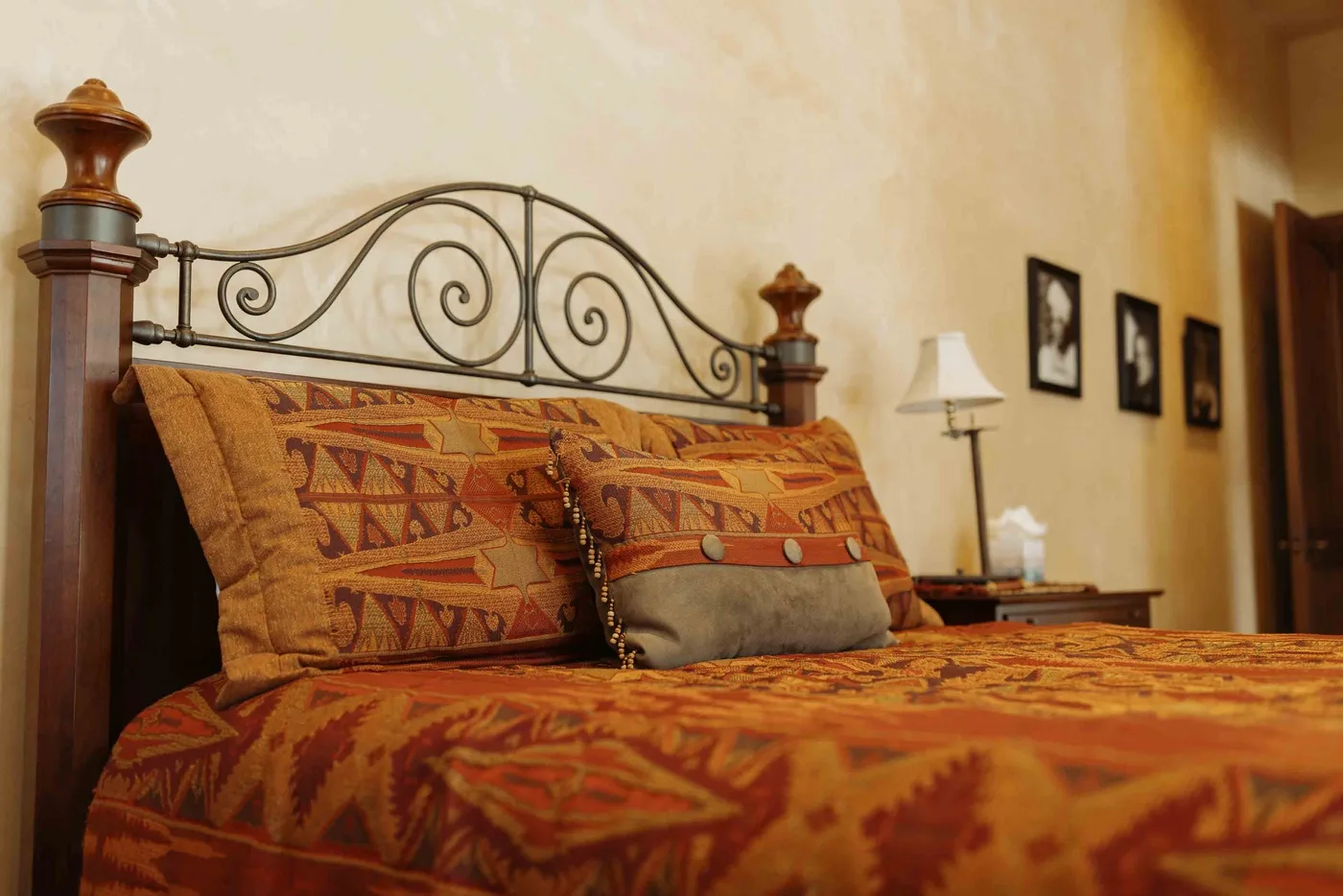 A bedroom with patterned bedding and an ornate metal headboard.