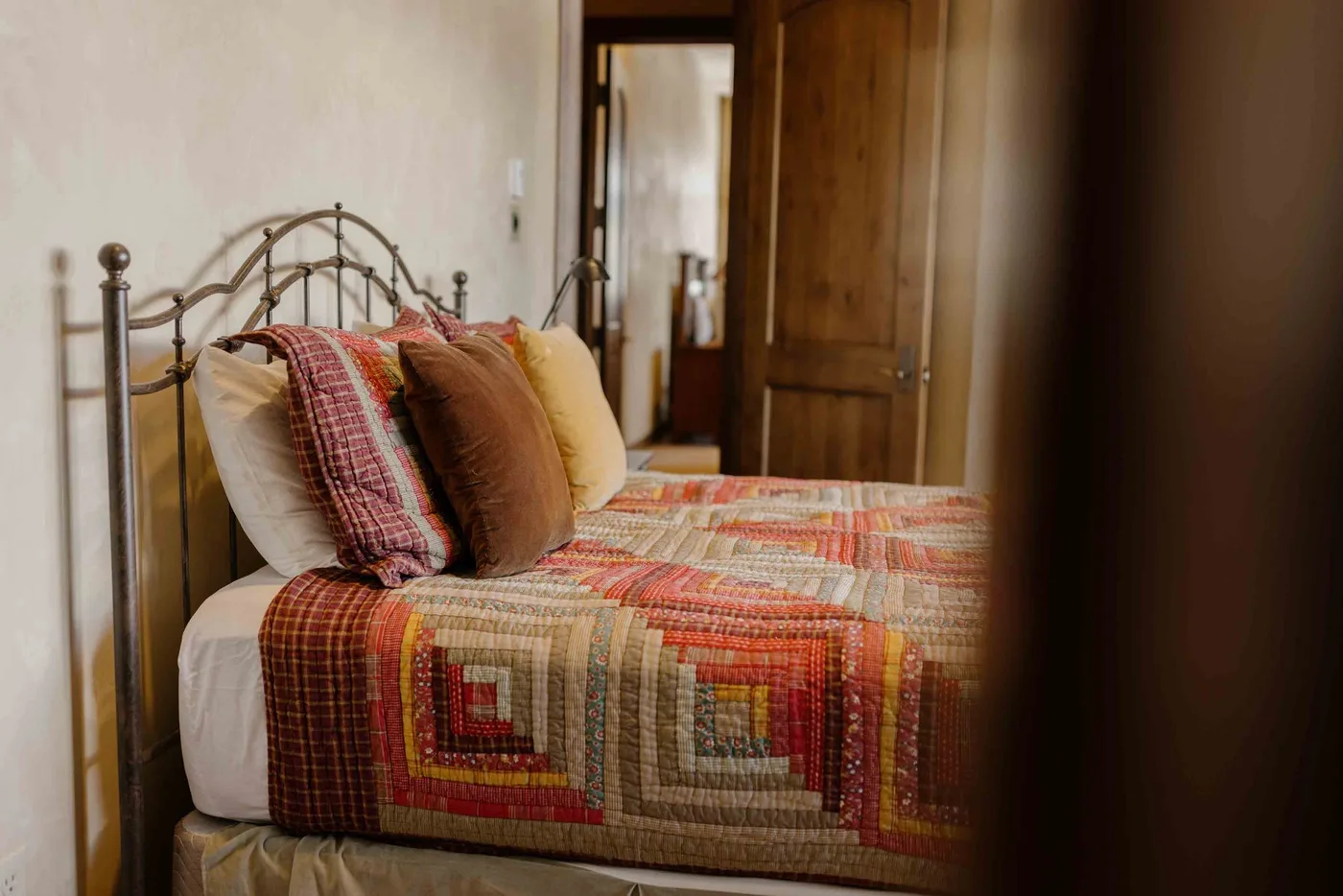 A bedroom with a bed covered in a colorful patchwork quilt.