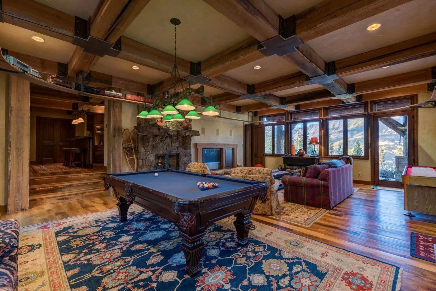 A recreation room with a pool table, seating, and large windows.