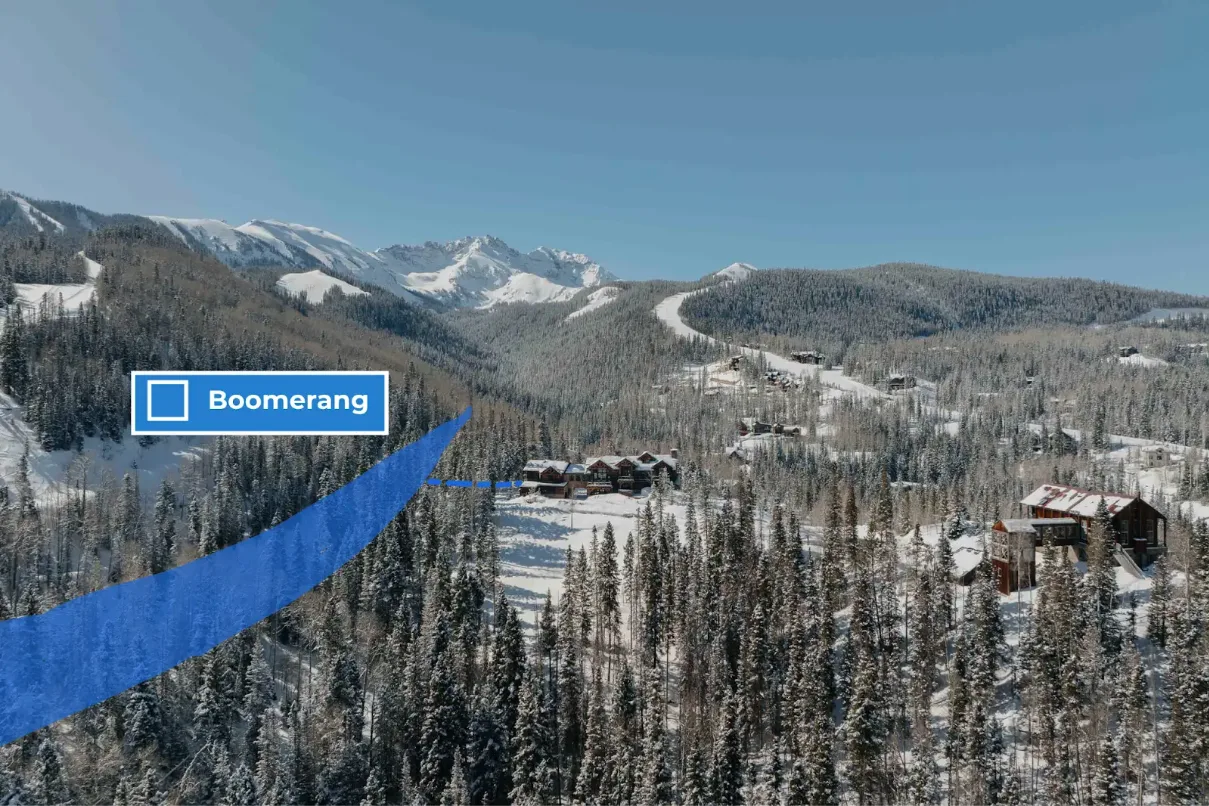 A snowy mountain landscape with forested slopes and scattered buildings.