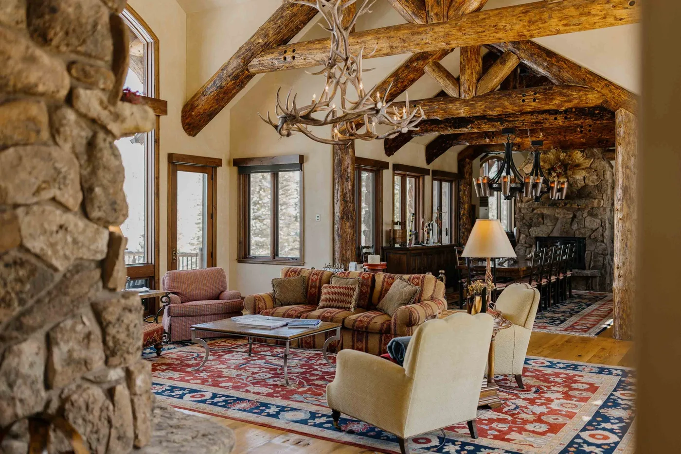 A rustic living room with seating arranged around a coffee table on a patterned rug.