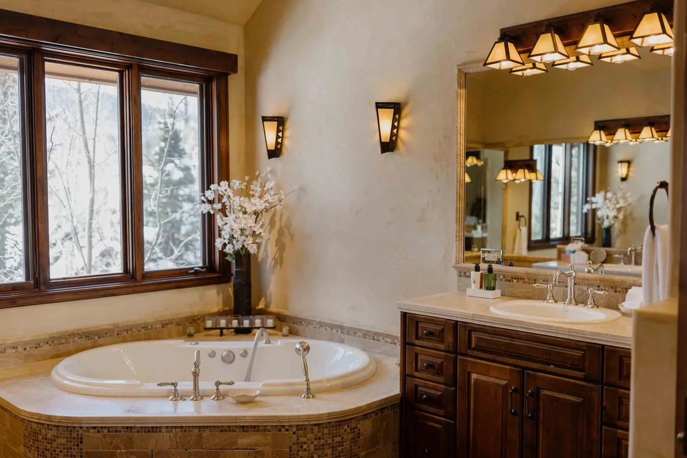 A bathroom with a large tub beside a wooden vanity and mirror.